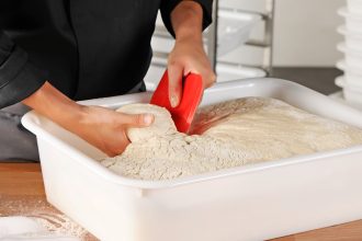 Dough Scrapers in use with pizza dough in food container.